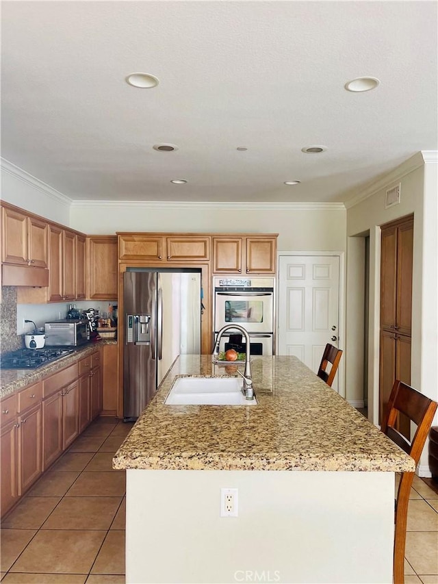 kitchen featuring a breakfast bar area, stainless steel appliances, a kitchen island with sink, light tile patterned flooring, and sink