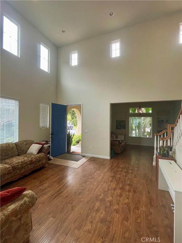 unfurnished living room featuring a healthy amount of sunlight, a towering ceiling, and wood-type flooring