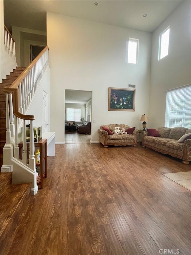 living room featuring hardwood / wood-style floors, a wealth of natural light, and a towering ceiling