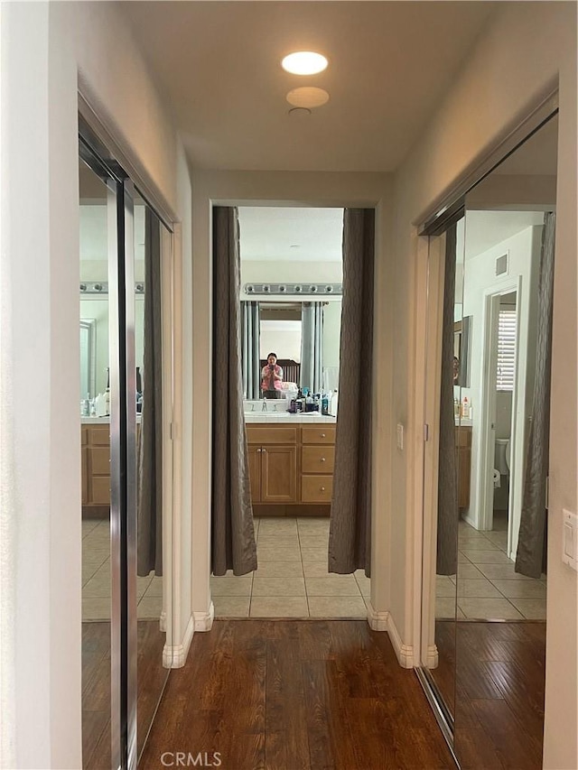 corridor with light wood-type flooring and sink