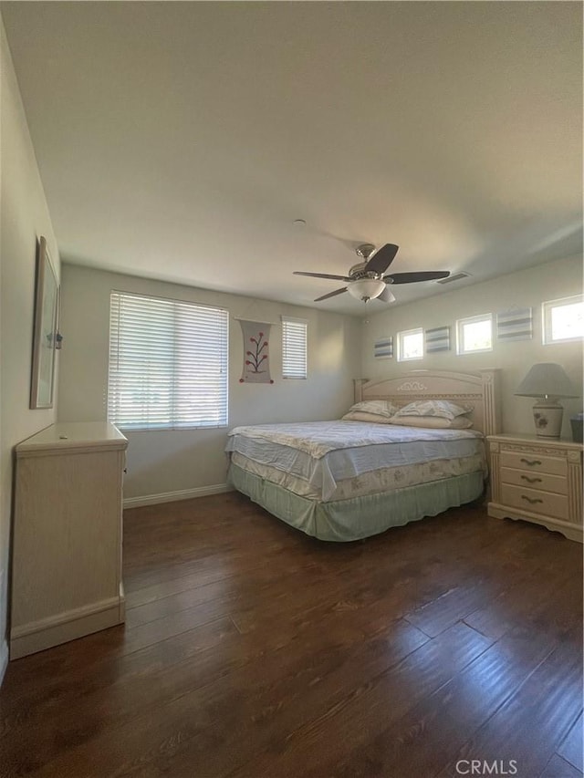 bedroom featuring ceiling fan, dark wood-type flooring, and multiple windows