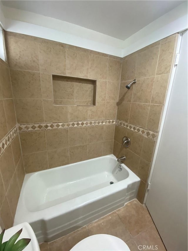 bathroom featuring tile patterned floors, toilet, and tiled shower / bath