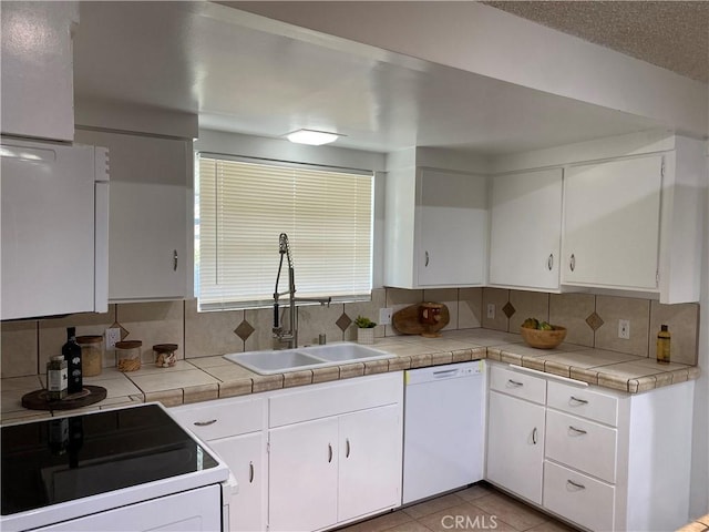 kitchen featuring tile counters, dishwasher, white cabinets, and stove