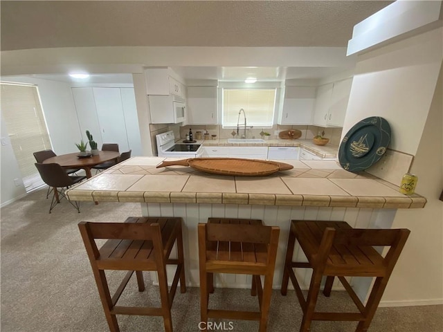 kitchen featuring white cabinets, white appliances, and a breakfast bar area