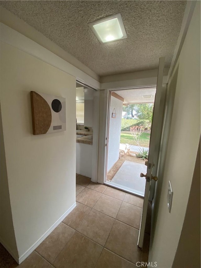 entryway featuring light tile patterned floors and a textured ceiling