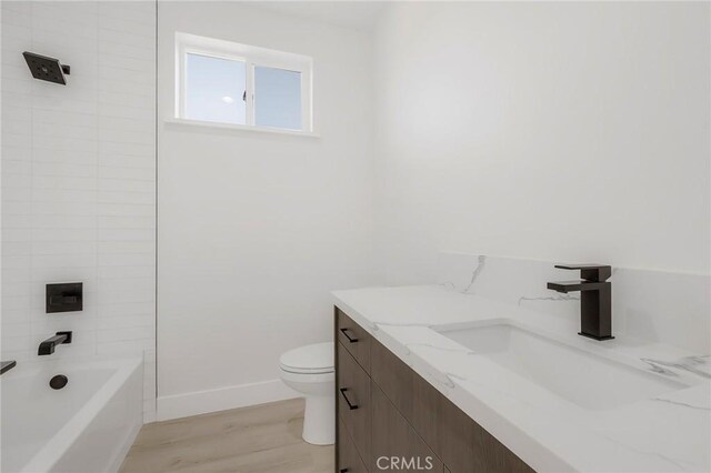 full bathroom featuring vanity, wood-type flooring, tiled shower / bath combo, and toilet