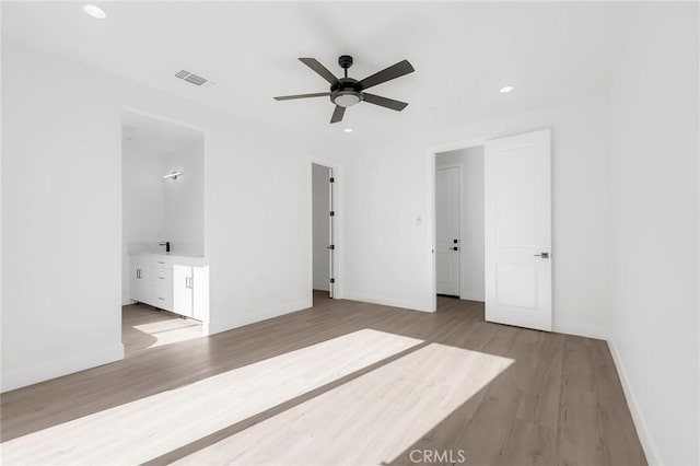 unfurnished bedroom featuring light hardwood / wood-style floors, ensuite bath, and ceiling fan