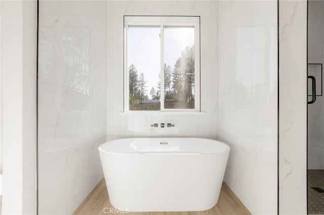 bathroom featuring wood-type flooring, tile walls, and plus walk in shower