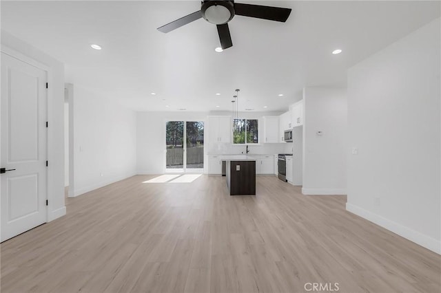 unfurnished living room with ceiling fan, light wood-type flooring, and sink