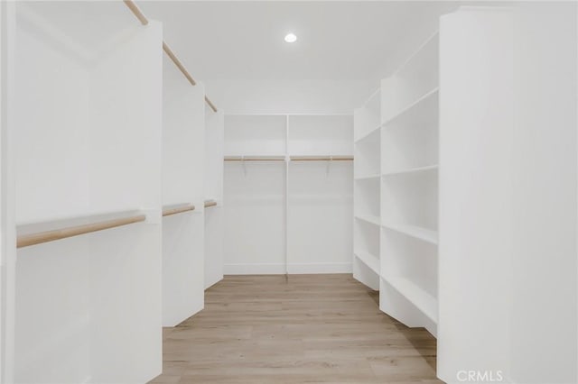 walk in closet with light hardwood / wood-style flooring