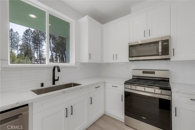 kitchen with white cabinetry, light stone countertops, sink, and appliances with stainless steel finishes