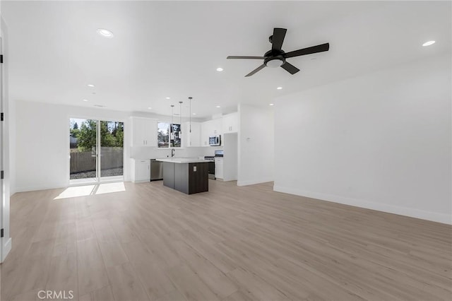 unfurnished living room with ceiling fan, sink, and light hardwood / wood-style flooring