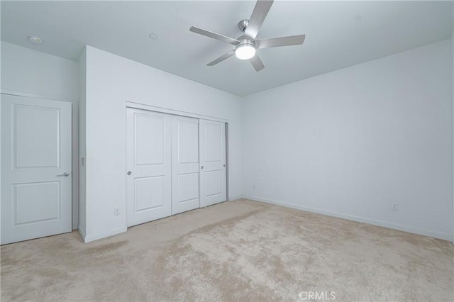 unfurnished bedroom with ceiling fan, light carpet, and a closet