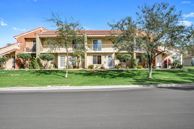 mediterranean / spanish house with a balcony and a front lawn