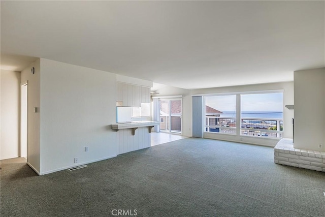 unfurnished living room with dark colored carpet and a wealth of natural light