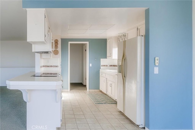 kitchen featuring white cabinetry, white fridge with ice dispenser, and a kitchen bar