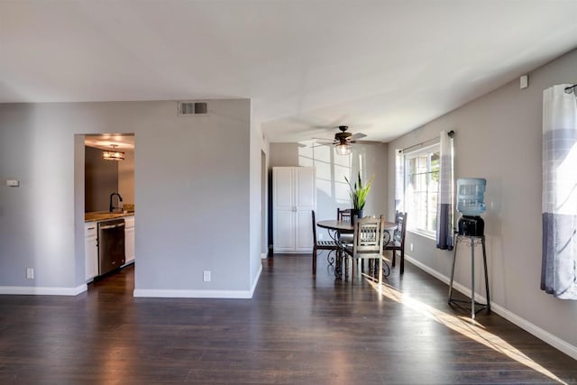 dining room featuring ceiling fan, sink, and dark wood-type flooring