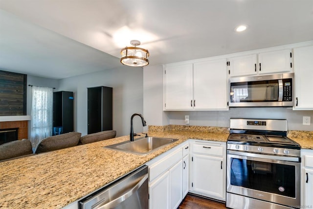 kitchen with sink, white cabinetry, dark hardwood / wood-style flooring, kitchen peninsula, and stainless steel appliances