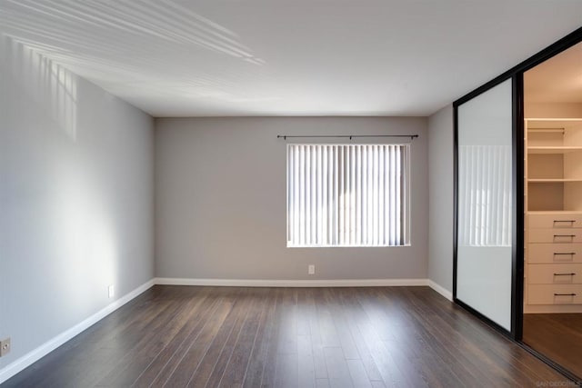 unfurnished bedroom with dark hardwood / wood-style floors, a spacious closet, and a closet