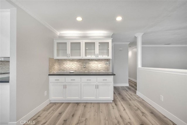 interior space featuring ornate columns, tasteful backsplash, crown molding, white cabinets, and light wood-type flooring