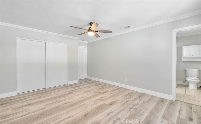 unfurnished bedroom with ceiling fan, ensuite bathroom, crown molding, a closet, and light wood-type flooring