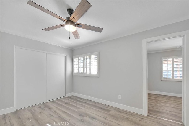 unfurnished bedroom with ceiling fan, light wood-type flooring, crown molding, and a closet