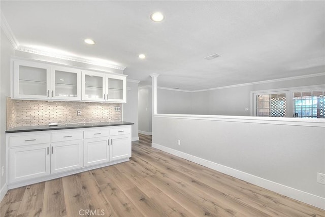 kitchen featuring decorative backsplash, light hardwood / wood-style floors, white cabinetry, and crown molding