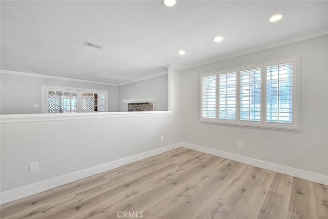 spare room with crown molding, light hardwood / wood-style flooring, and a healthy amount of sunlight