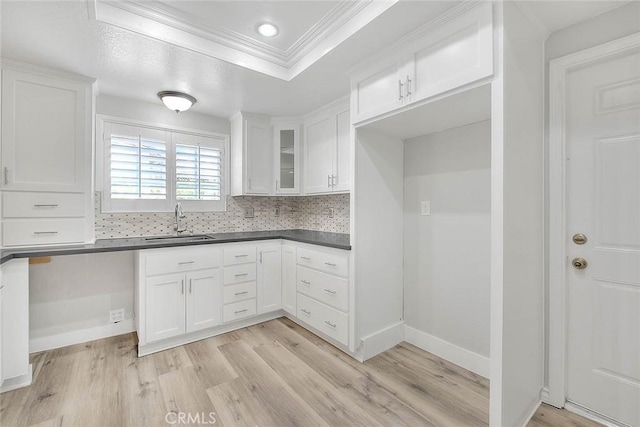 kitchen with light wood-type flooring, white cabinetry, crown molding, and sink