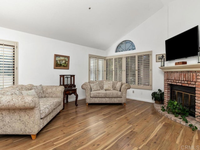 living room with hardwood / wood-style flooring, high vaulted ceiling, and a brick fireplace