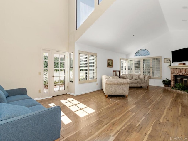 living room featuring a fireplace, light hardwood / wood-style floors, and a high ceiling