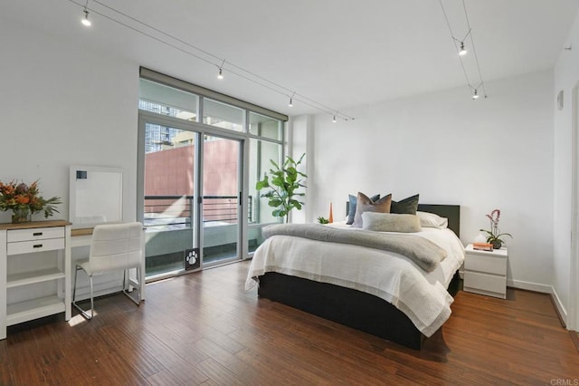 bedroom with dark hardwood / wood-style flooring, access to exterior, and track lighting