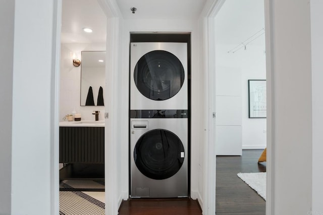 clothes washing area featuring sink, dark hardwood / wood-style flooring, and stacked washer / dryer