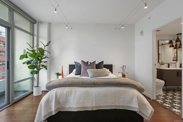 bedroom with dark hardwood / wood-style floors, track lighting, and sink