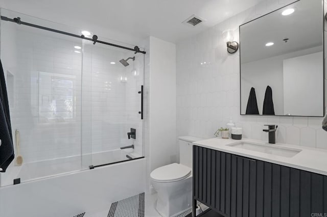 full bathroom with decorative backsplash, bath / shower combo with glass door, vanity, tile patterned flooring, and toilet