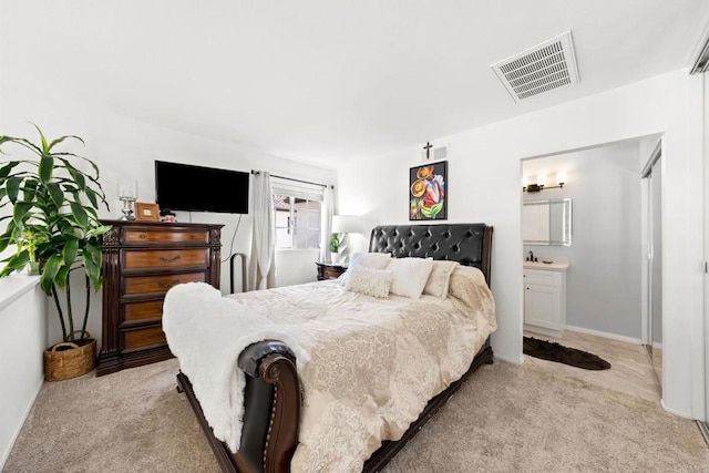 bedroom with light colored carpet and connected bathroom