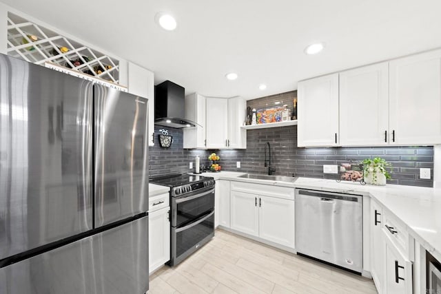 kitchen featuring white cabinets, sink, wall chimney range hood, and stainless steel appliances