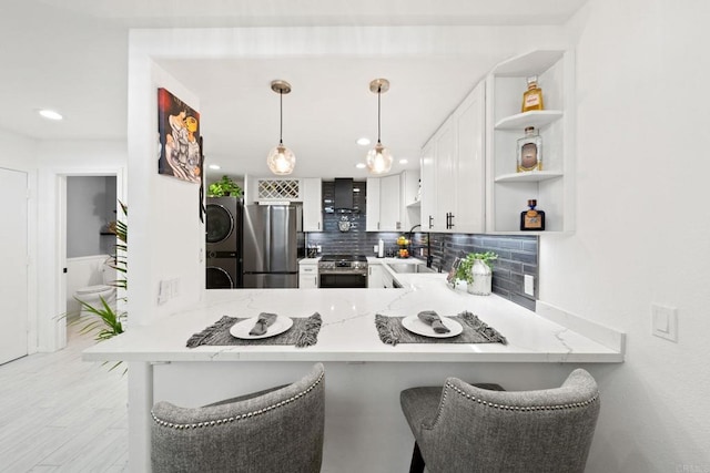 kitchen featuring white cabinetry, wall chimney range hood, a kitchen breakfast bar, kitchen peninsula, and appliances with stainless steel finishes