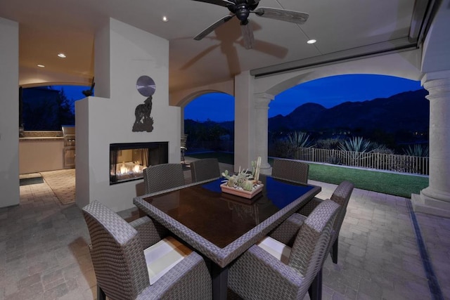 patio at twilight with a multi sided fireplace and ceiling fan