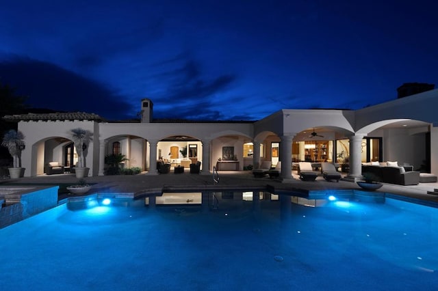 pool at twilight featuring a patio area, ceiling fan, and an outdoor hangout area