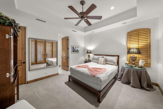 bedroom with a tray ceiling, ceiling fan, and light colored carpet