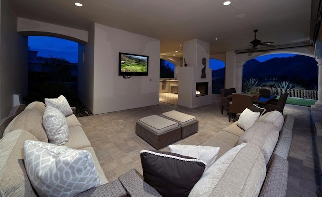 view of patio / terrace with an outdoor living space with a fireplace and ceiling fan