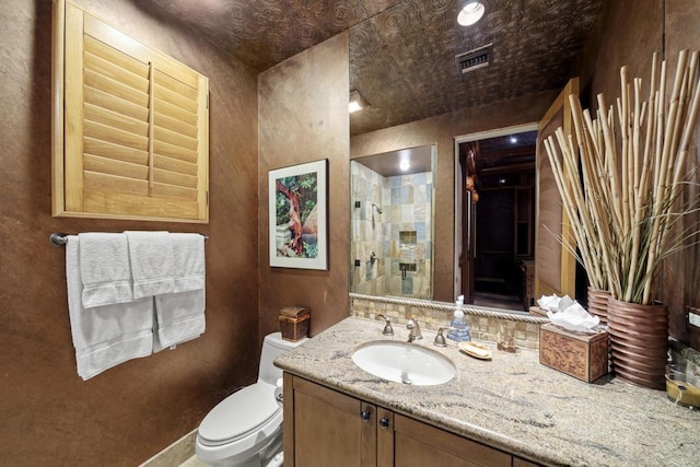 bathroom with vanity, toilet, and a tile shower