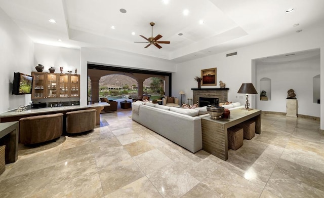 living room with a tray ceiling and ceiling fan