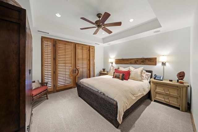 carpeted bedroom featuring ceiling fan and a raised ceiling