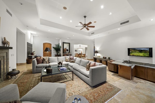 living room with ceiling fan and a raised ceiling