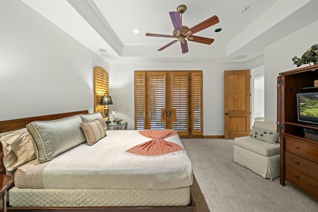 bedroom with a tray ceiling, ceiling fan, and light colored carpet