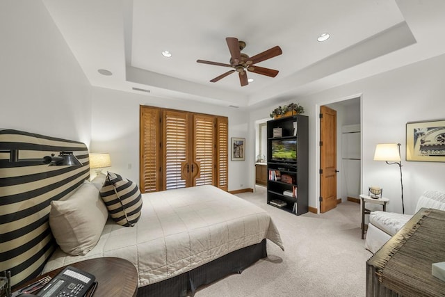 bedroom with a tray ceiling, ceiling fan, and light colored carpet