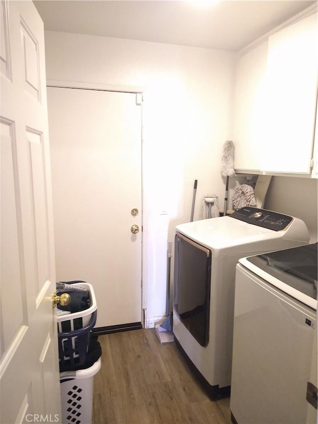 laundry room featuring cabinets, dark hardwood / wood-style floors, and washing machine and clothes dryer