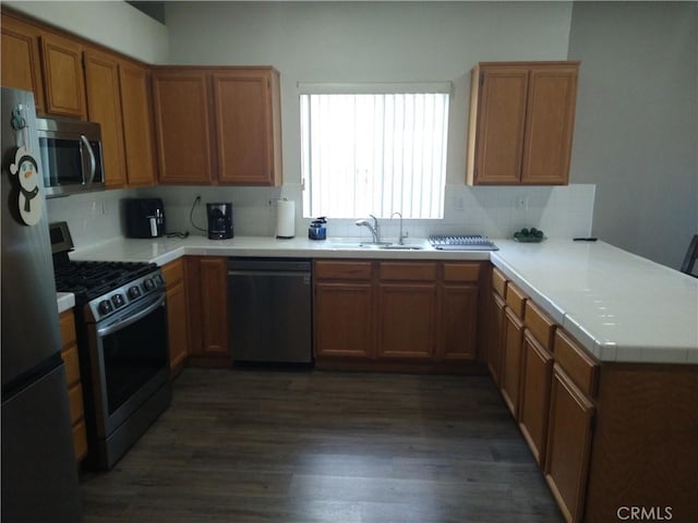 kitchen with sink, backsplash, stainless steel appliances, dark hardwood / wood-style floors, and kitchen peninsula